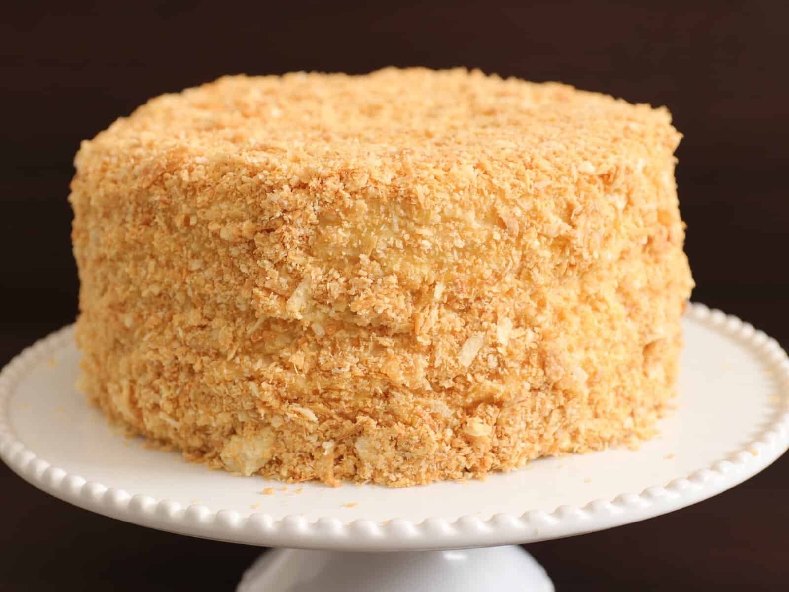 Russian Napolean cake coated with crumbs on a white serving plate