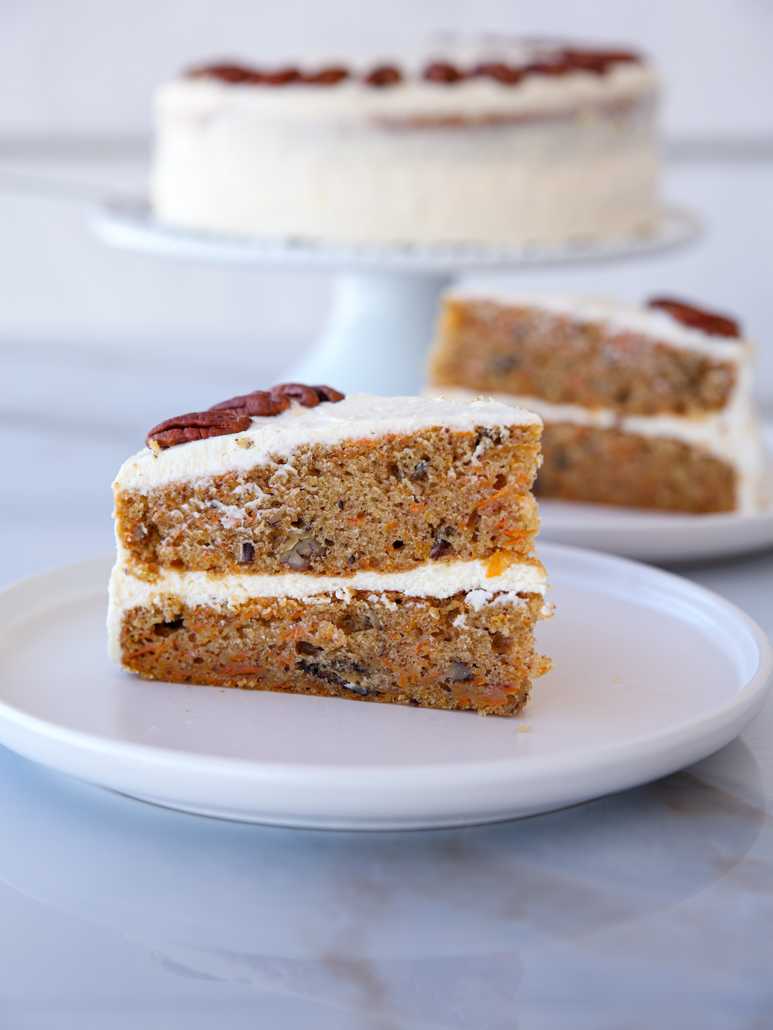 a slice of moist carrot cake with cream cheese frosting on a white plate