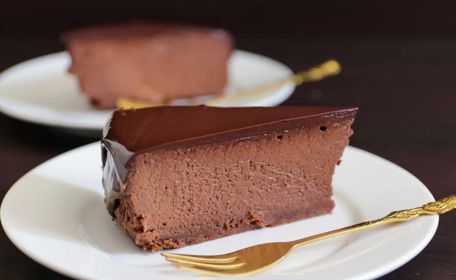 a slice of chocolate cheesecake covered with a silky dark chocolate ganache 