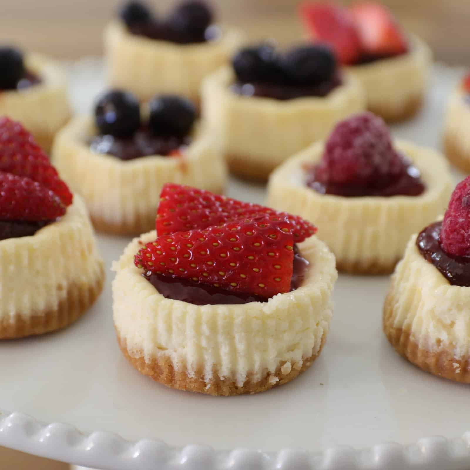 mini cheesecakes topped with jam and fresh berries