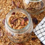 a jar of homemade granola and freshly baked granola is on the counter