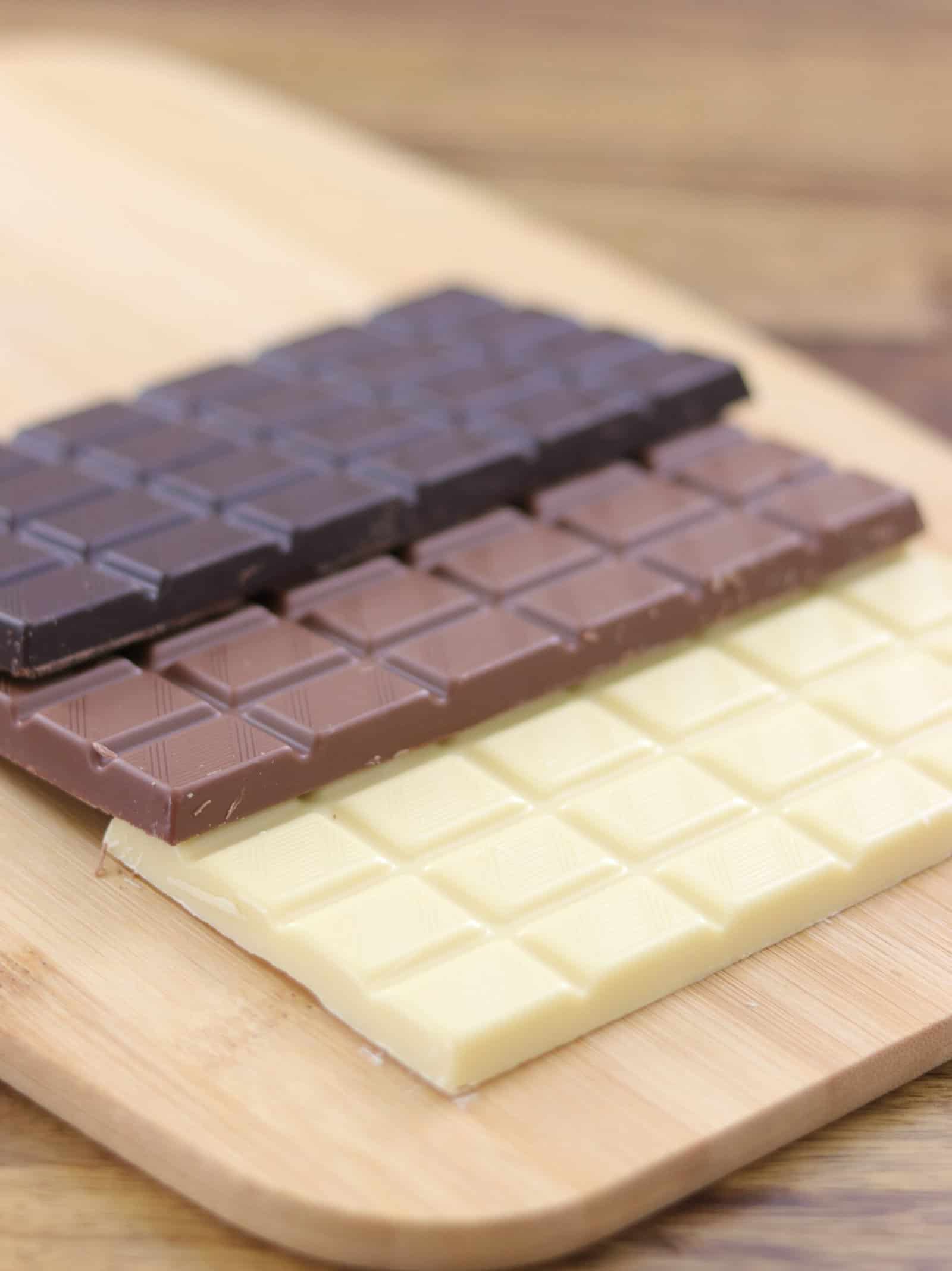 white chocolate, milk chocolate and dark chocolate bars on a cutting board