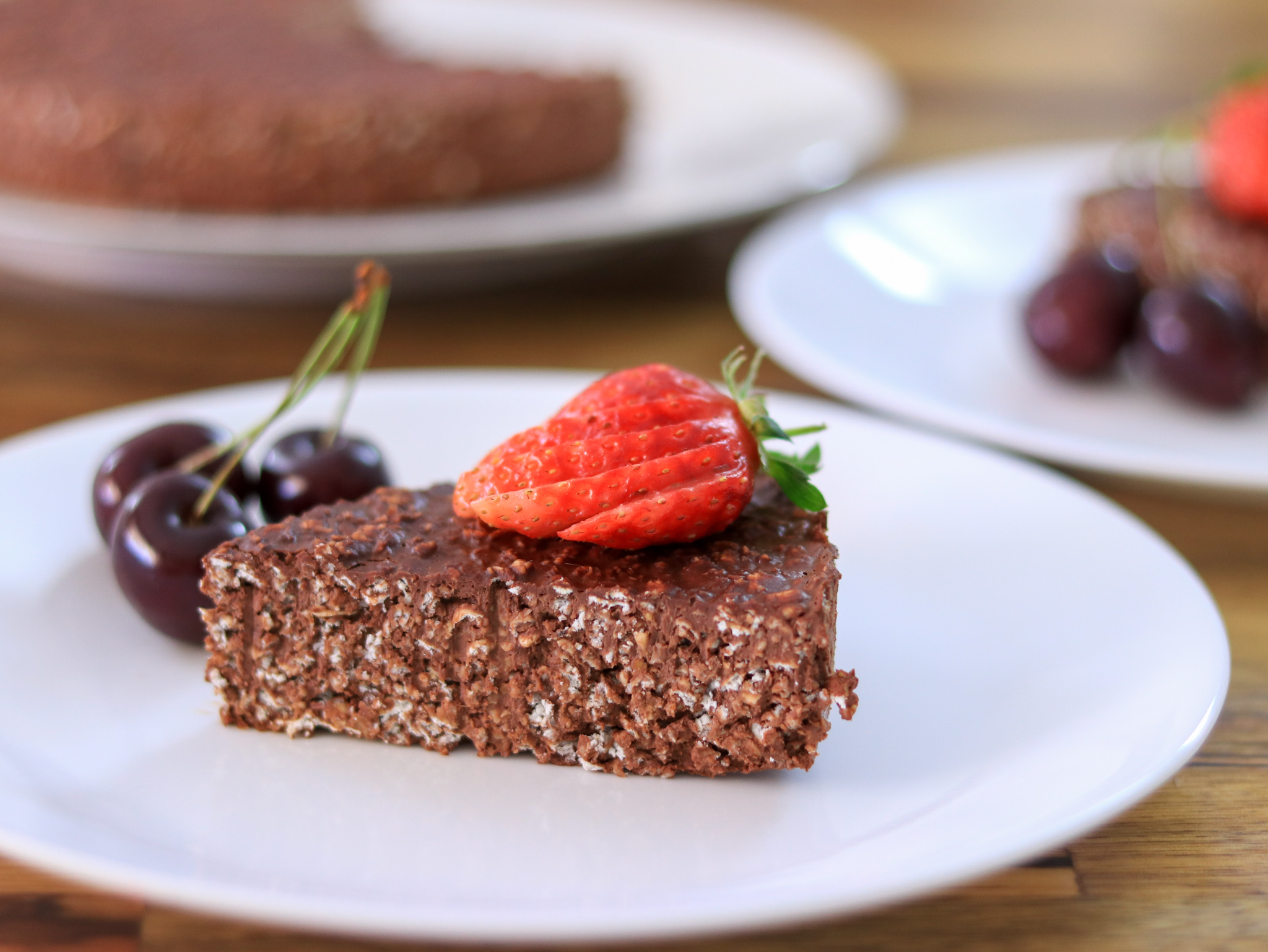 3-ingredient chocolate oatmeal cake topped with fresh strawberries and cherries