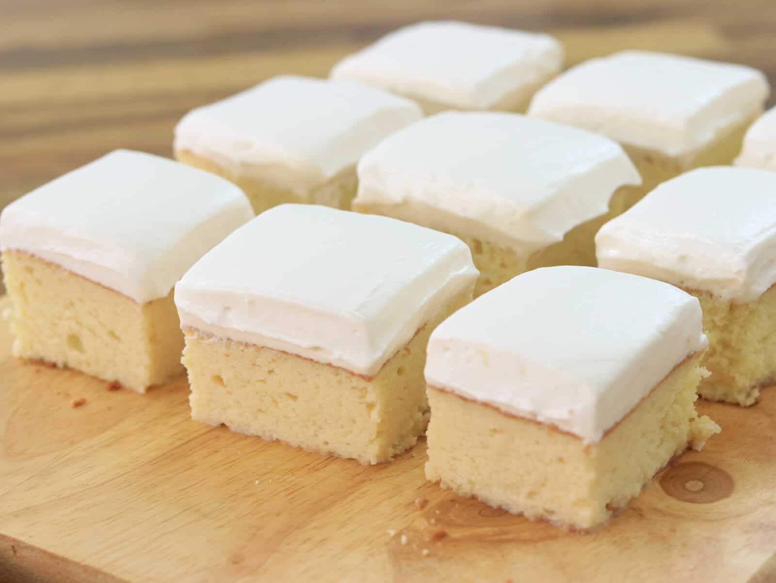 9 pieces of sponge cake on topped with whipped cream on a cutting board