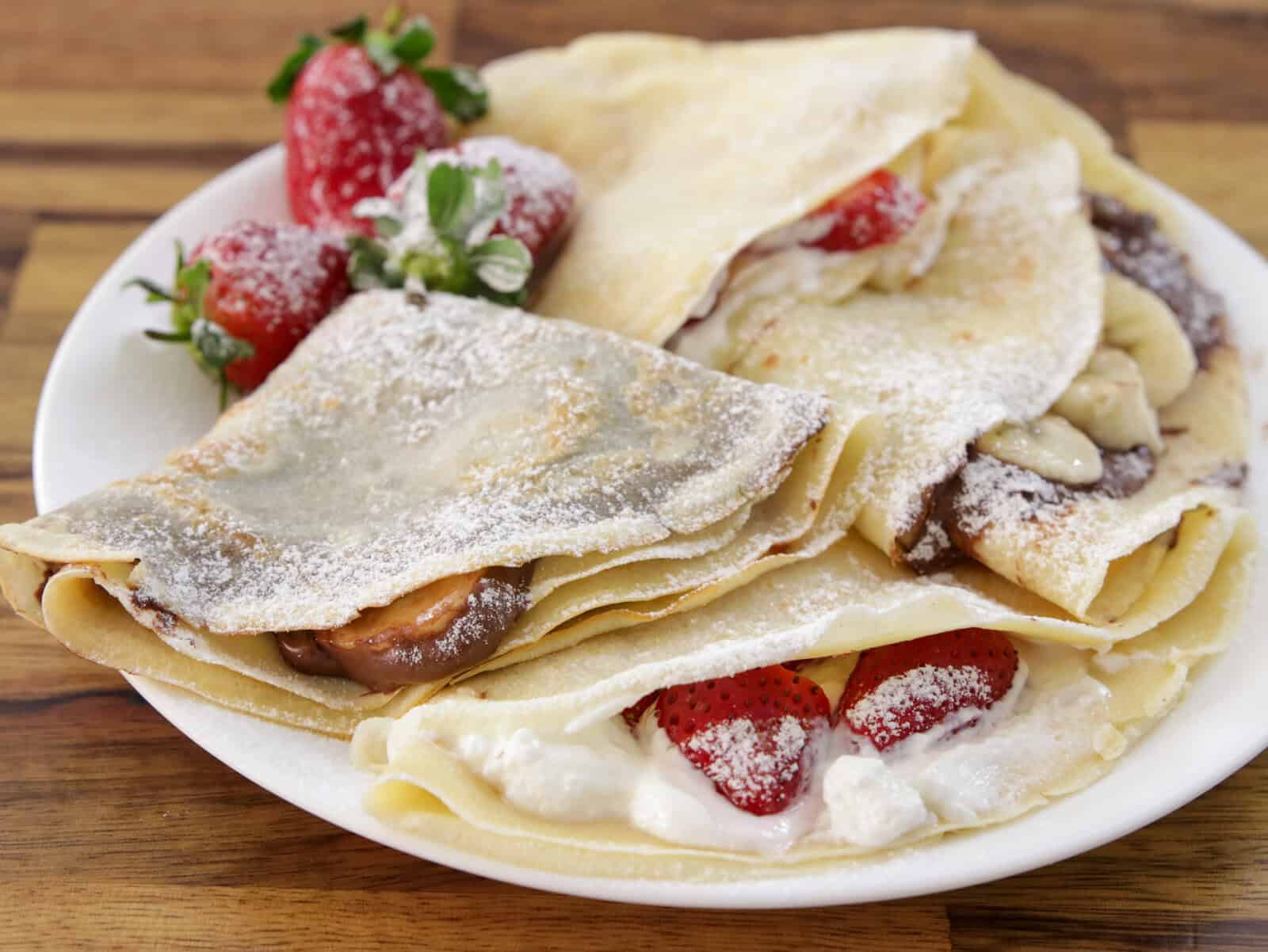 french crepes with chocolate, banana, strawberries and powdered sugar