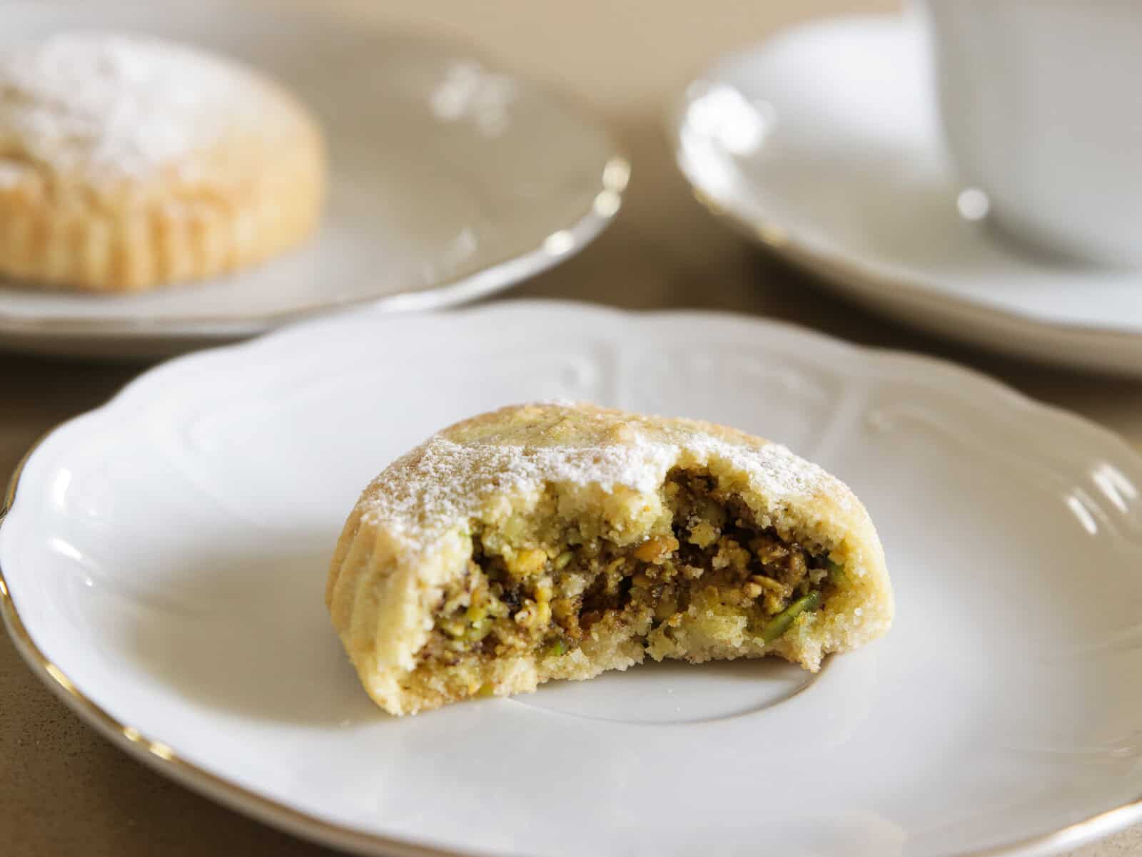 a bitten pistachio maamoul on a white plate