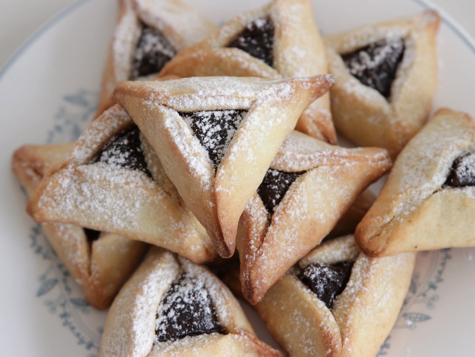 Hamantaschen cookies on a plate dust with powdered sugar