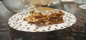 A slice of layered caramel icebox cake on a paper plate with a brown polka dot pattern.