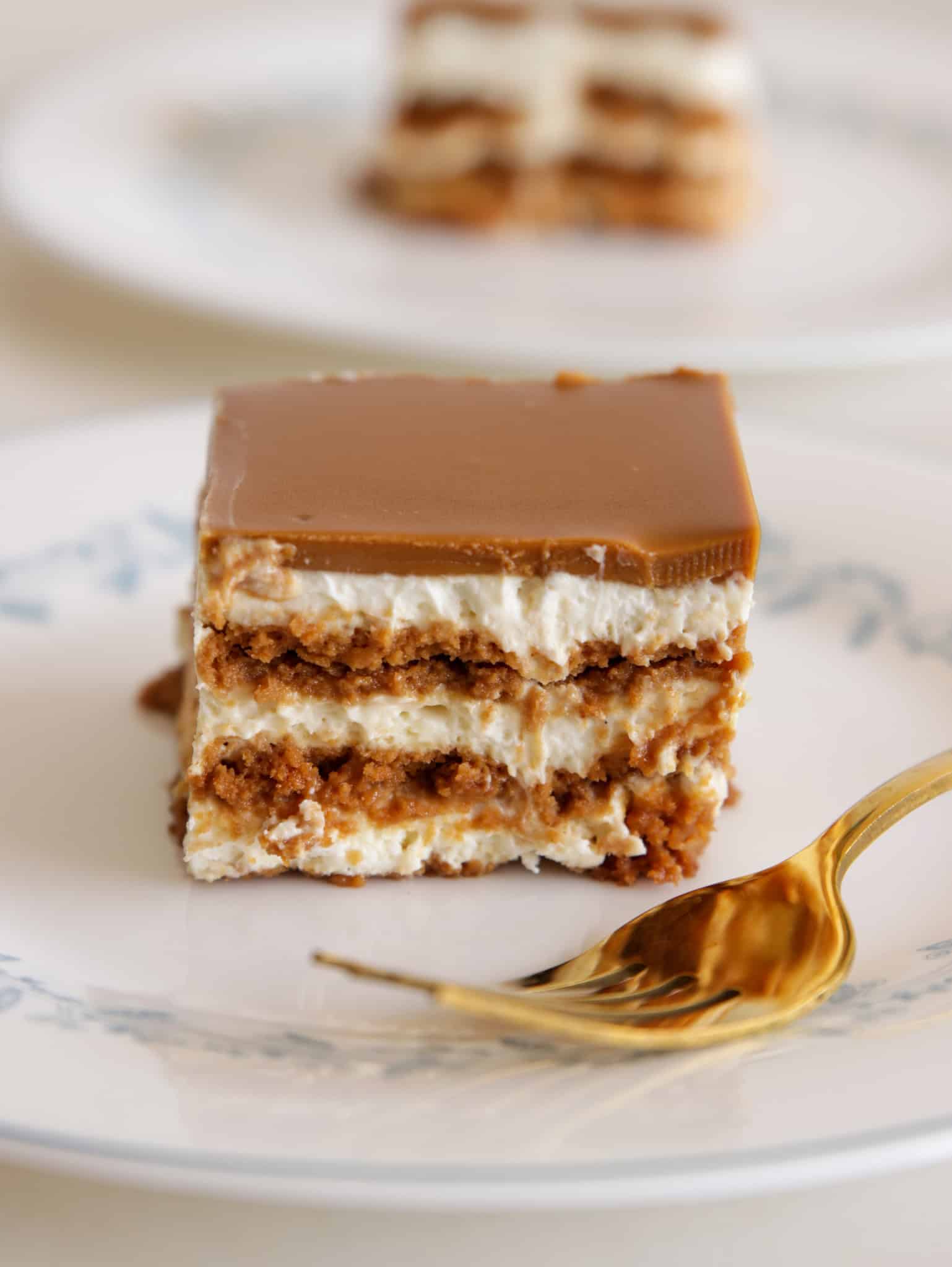 Layered Lotus Biscoff Cake on a white plate with a golden fork