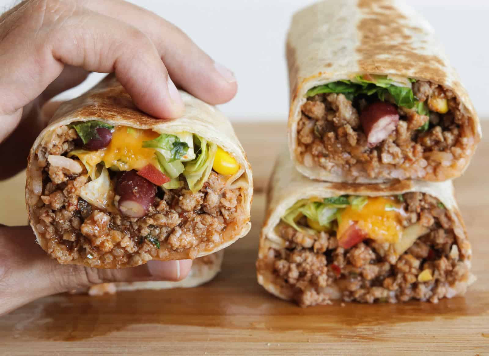 a hand is holding beef burrito