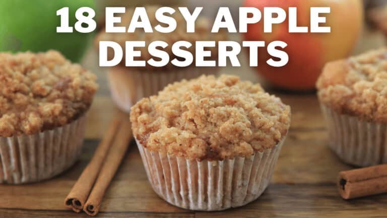 Four apple crumble muffins in white paper liners are displayed on a wooden surface, surrounded by cinnamon sticks and whole apples. The text "18 Easy Apple Desserts" is prominently featured above the muffins.