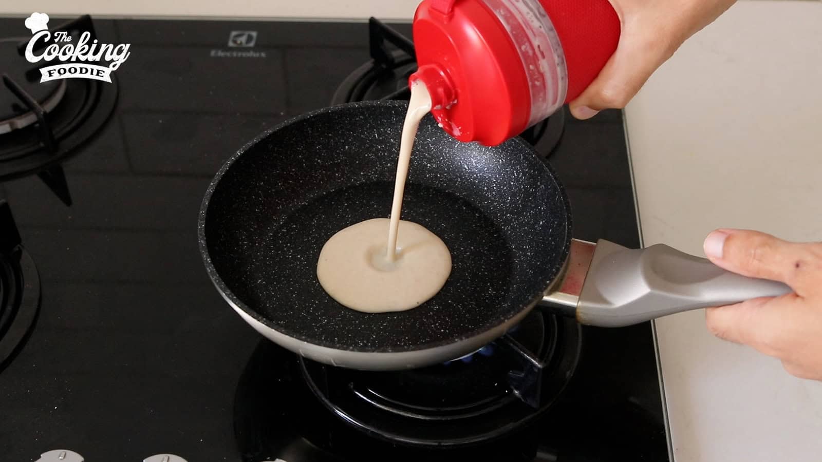 pouring crepe batter into a pan