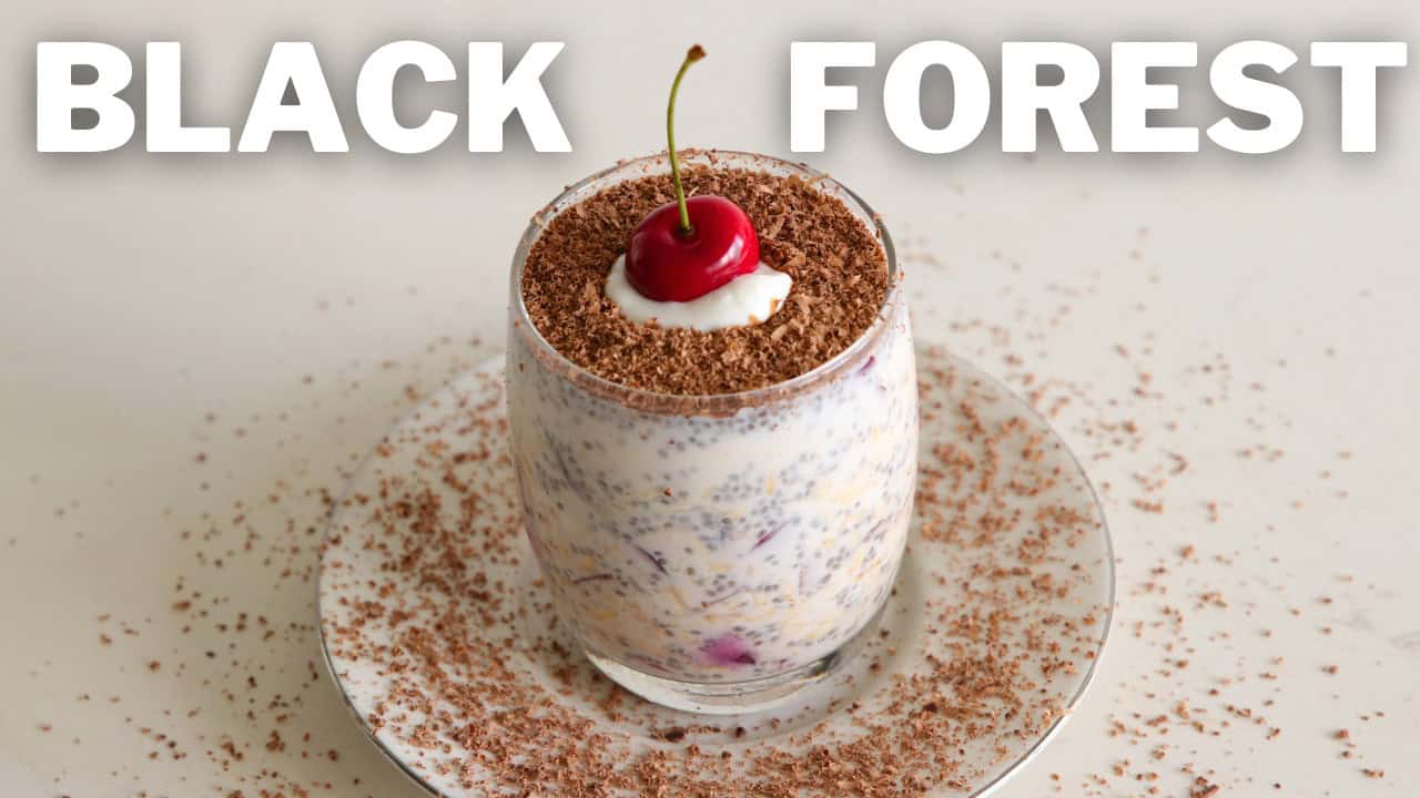 A dessert in a clear glass, topped with a dollop of cream, a cherry, and chocolate shavings. The glass sits on a white plate, which is also sprinkled with chocolate shavings. The words "BLACK FOREST" are written in bold white letters at the top of the image.