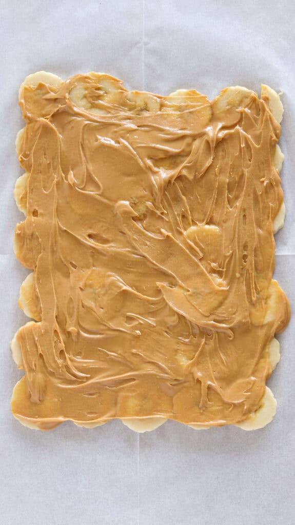 a layer of natural peanut butter on a layer of sliced bananas 