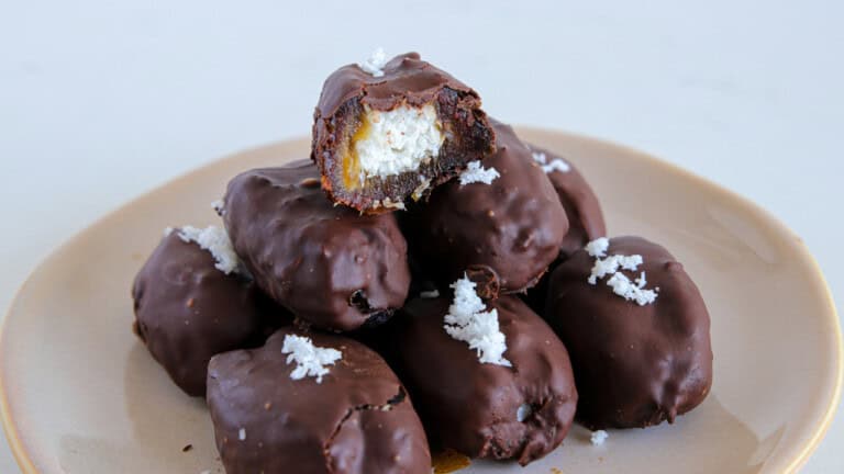 A plate of Bounty Dates, which are dates covered in a chocolate coating and topped with shredded coconut. The text "Bounty Dates" is prominently displayed over the image.