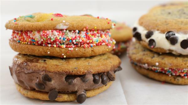 Two ice cream sandwiches are shown, each made with cookies as the outer layers. The left sandwich has chocolate chip cookies with chocolate ice cream and chocolate chips, while the right sandwich features cookies with vanilla ice cream and rainbow sprinkles.