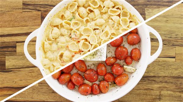 A circular white baking dish is divided diagonally. The left half contains creamy pasta shells, while the right half has roasted cherry tomatoes, a block of cheese, and garlic cloves on a wooden surface.