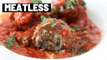 A close-up of meatless meatballs covered in tomato sauce, garnished with green herbs. One meatball is cut open, revealing a textured, plant-based filling. The top-left corner has bold, black and white text that reads "MEATLESS.