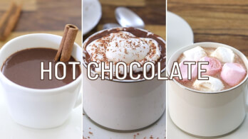 A three-panel image showcasing different styles of hot chocolate. The first cup has a cinnamon stick, the second is topped with whipped cream and cocoa powder, and the third has marshmallows. "HOT CHOCOLATE" is written across the image.