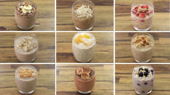 A grid of nine clear glass cups, each filled with different variations of overnight oats. Toppings include sliced bananas, shredded coconut, strawberries, blueberries, nuts, and granola. The cups are arranged in a 3x3 pattern on a wooden surface.