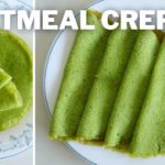 A plate of green oatmeal crepes is displayed with one crepe folded in the foreground and several crepes folded on a plate in the background. The text "OATMEAL CREPES" is written in large white letters at the top of the image.