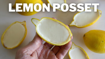 Hand holding half a lemon filled with creamy posset. Several lemon halves filled with posset are arranged on a surface. The text "LEMON POSSET" is placed prominently at the top of the image.