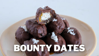 A plate of Bounty Dates, which are dates covered in a chocolate coating and topped with shredded coconut. The text "Bounty Dates" is prominently displayed over the image.