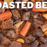 A close-up of a dish labeled "Roasted Beef" featuring chunks of beef, carrots, potatoes, and onions in a rich, dark sauce. The ingredients appear to be well-cooked and seasoned, with the beef looking tender and juicy.