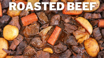 A close-up of a dish labeled "Roasted Beef" featuring chunks of beef, carrots, potatoes, and onions in a rich, dark sauce. The ingredients appear to be well-cooked and seasoned, with the beef looking tender and juicy.