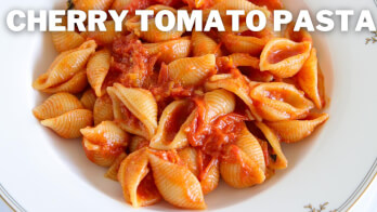 A white plate filled with shell pasta in a cherry tomato sauce, garnished with small herbs. At the top of the image, there is bold white text that reads "CHERRY TOMATO PASTA.