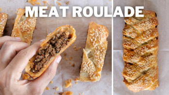 A close-up of a hand holding a slice of meat roulade, showing the savory meat filling inside flaky pastry. Next to it, a whole uncut meat roulade garnished with sesame seeds is placed on parchment paper. The text "MEAT ROULADE" is written at the top.