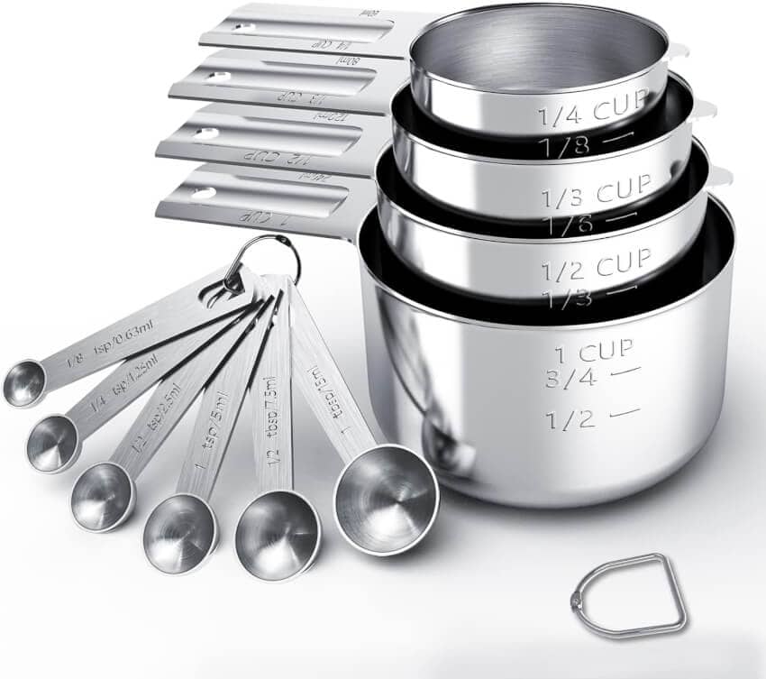 A set of stainless steel measuring cups and measuring spoons, ranging from 1/4 teaspoon to 1 cup. The cups are stacked, and the spoons are attached by a ring. Each piece has labeled measurements engraved on them for precision in cooking and baking.