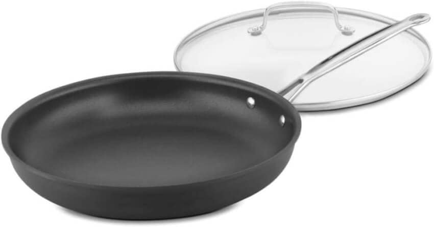 A non-stick black frying pan with a metal handle is placed next to a transparent glass lid with a metal rim and handle. The frying pan appears to be of medium size, and the lid fits it perfectly. The background is plain white.