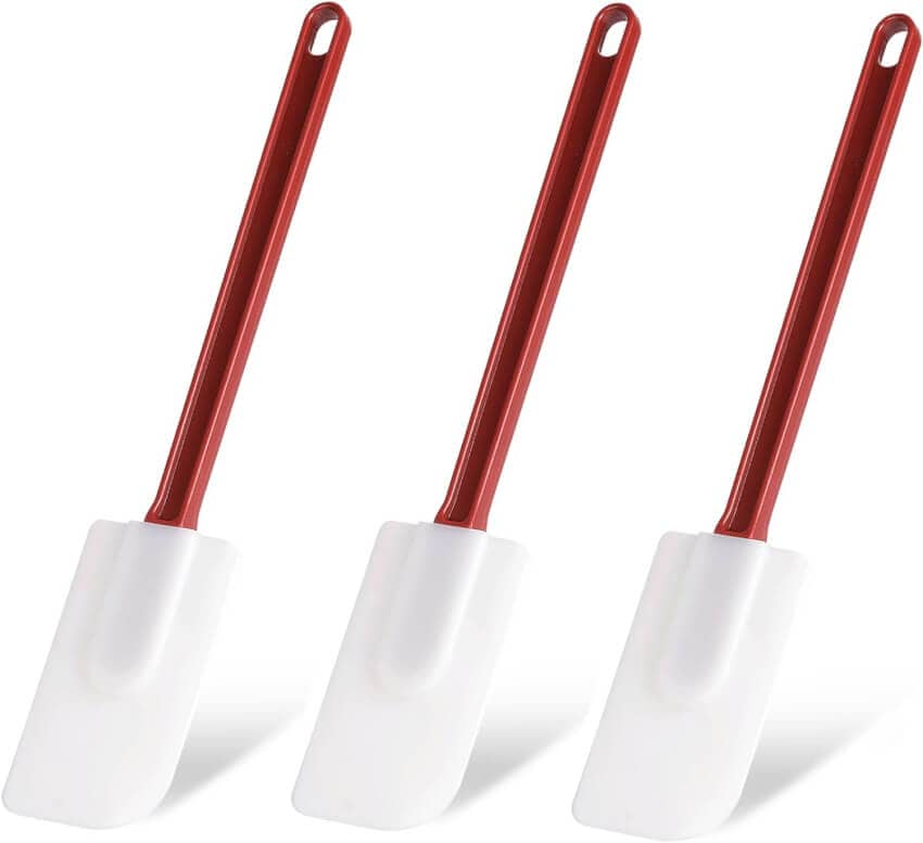 Three red-handled, white silicone spatulas are arranged side by side, each with a hole for hanging at the top of the handle. The spatulas have rectangular, flat heads.