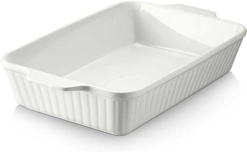 A rectangular white ceramic baking dish with a glossy finish and ribbed sides. It has a wide handle on one end and a smaller indentation on the other. The dish is empty and appears clean and ready for use.