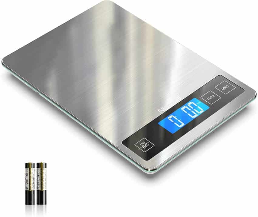 A sleek digital kitchen scale with a brushed stainless steel surface, featuring a glossy blue backlit LCD display showing "0.00." There are three buttons below the display labeled 'ON/OFF,' 'TARE,' and 'UNIT.' Two AAA batteries are shown next to the scale.