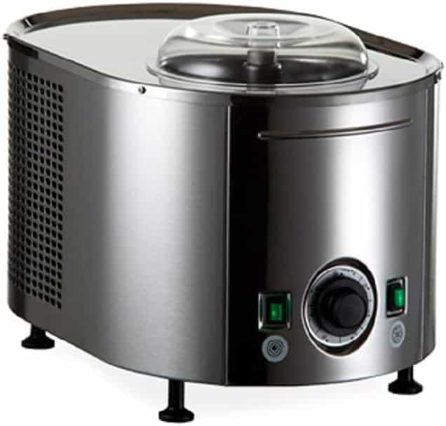 A stainless steel ice cream maker with a transparent lid is shown. It has a control knob and two buttons on the front, green and black. The appliance stands on four small legs with a vented side panel.