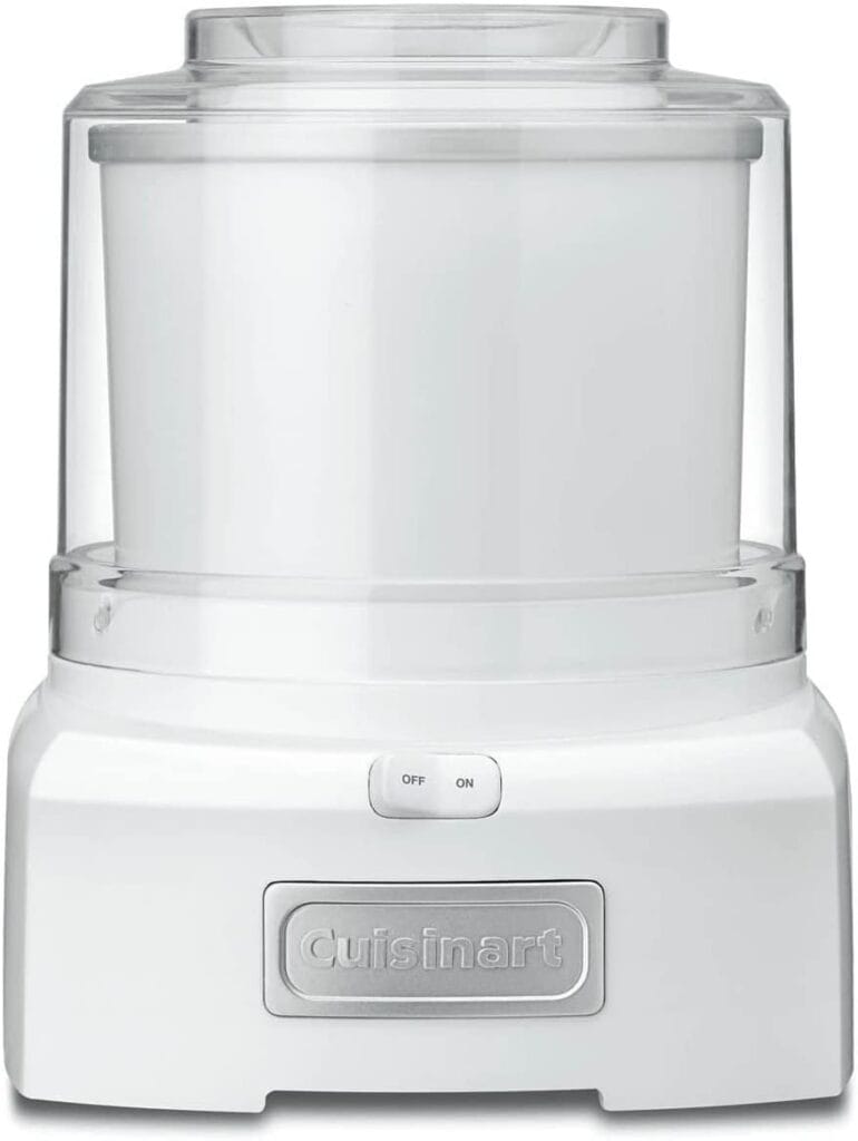 A white Cuisinart ice cream maker with an on/off switch on the front and a transparent lid on top. The Cuisinart logo is visible on the front panel. The design is sleek and modern.