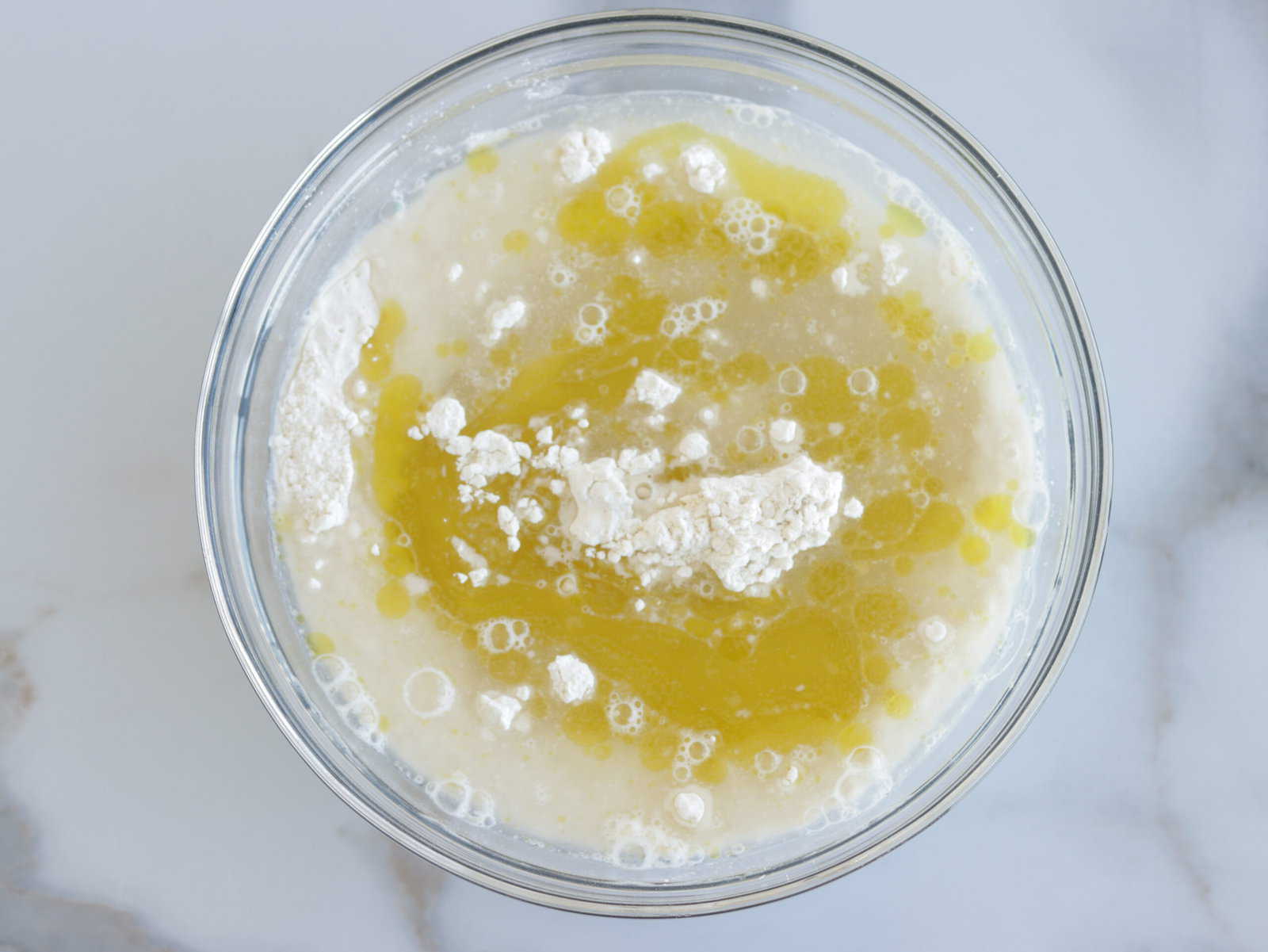 water and olive oil added to a bowl with flour, sugar, salt and yeast