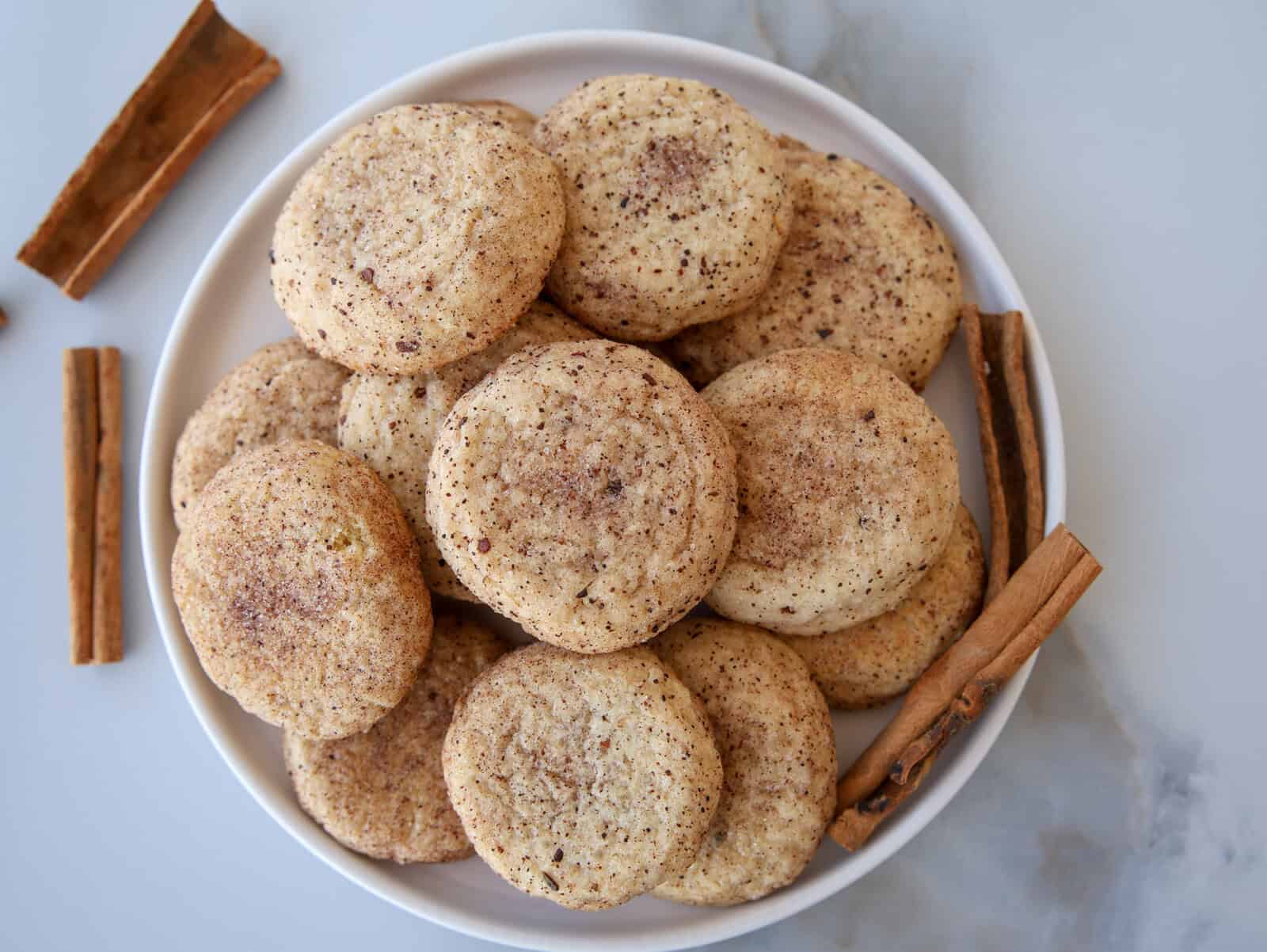 snickerdoodle cookies on a white plate with cinnamon sticks