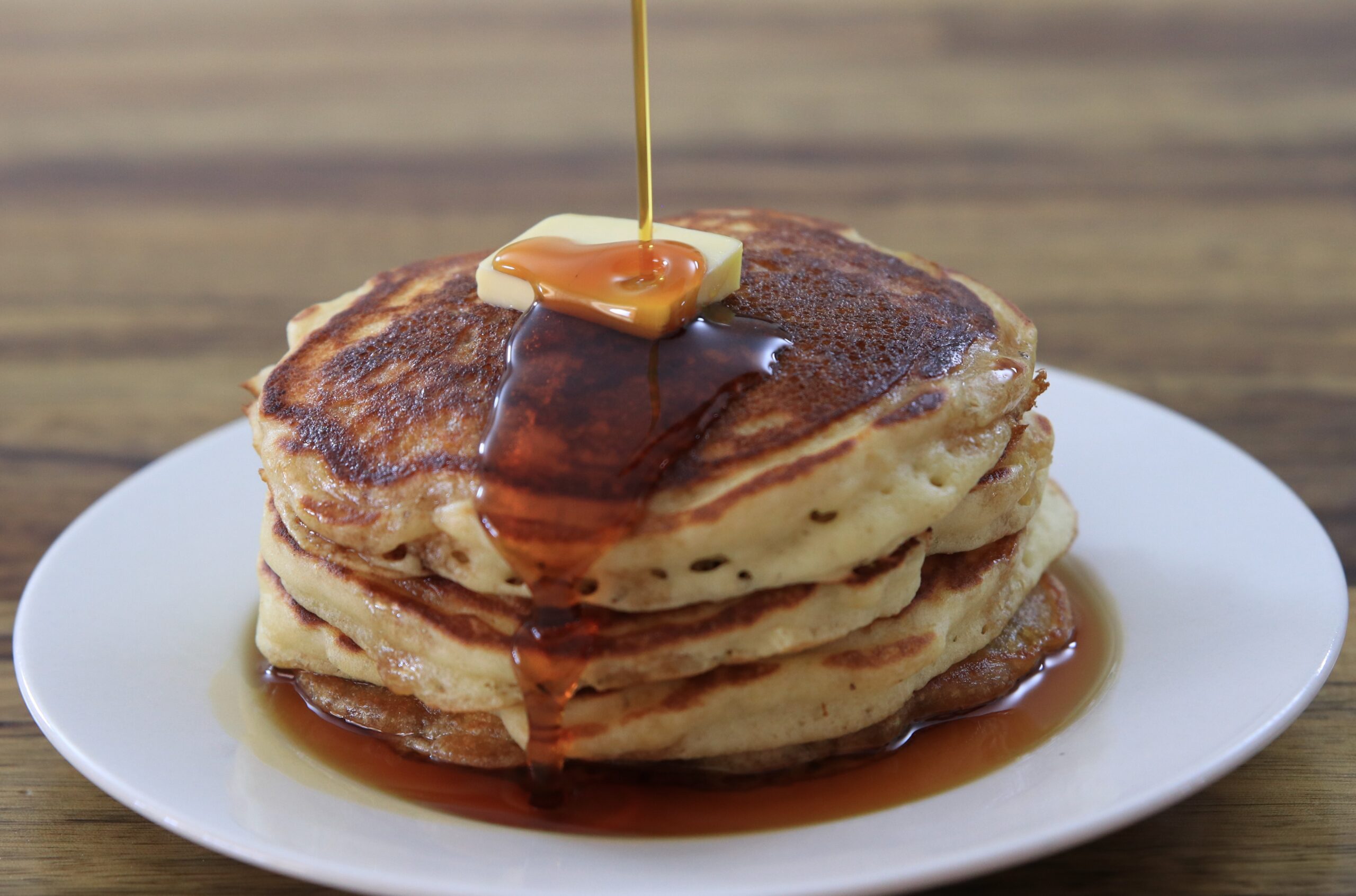 fluffy pancakes with a piece of butter on top and a drizzle of maple syrup