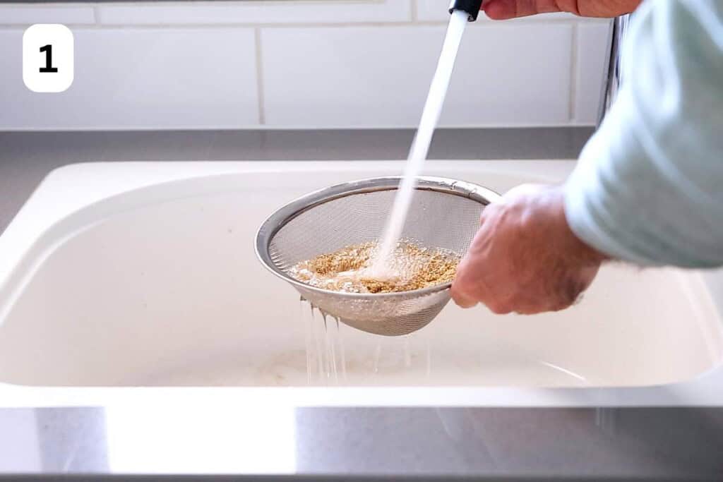 rinsing quinoa in a mesh strainer under water.