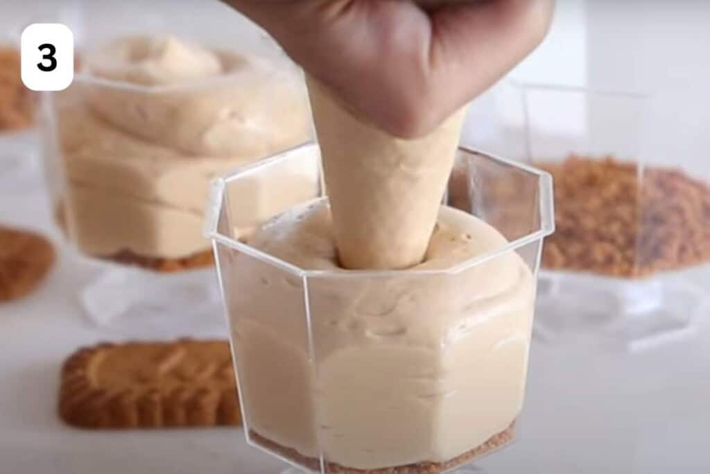 piping biscoff mousse in serving cups.