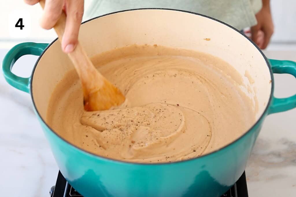 spoon mixing a creamy cauliflower soup.