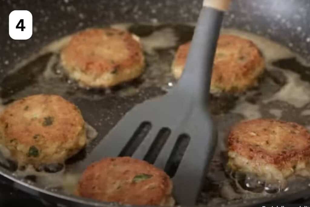 spatula frying tuna patties in a pan.