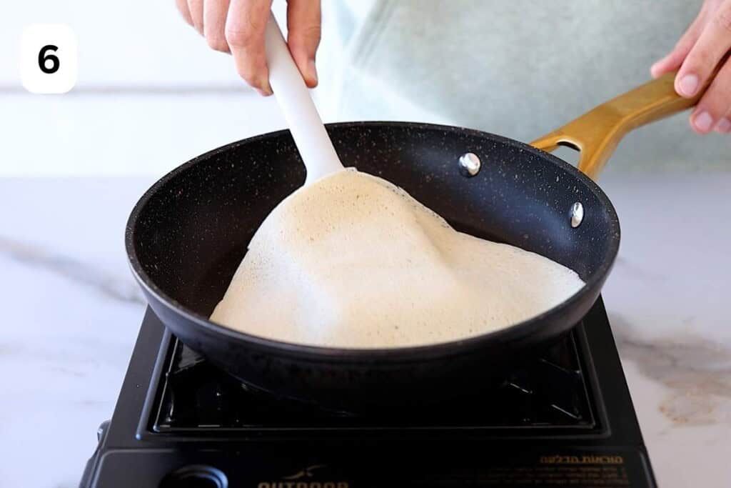 spatula flipping a crepe in a pan.