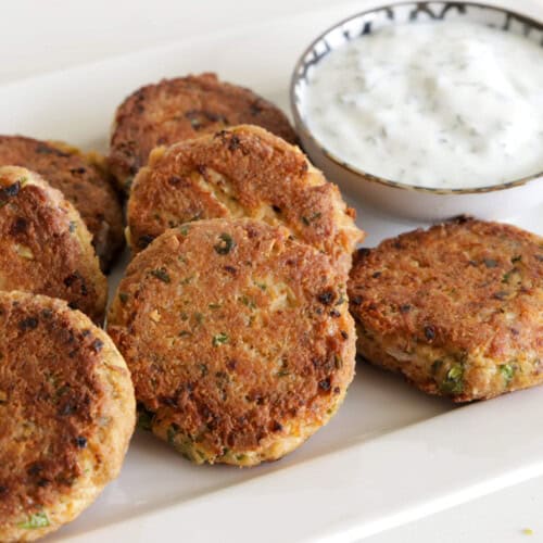 Tuna patties on a white plate along side with white dipping sauce