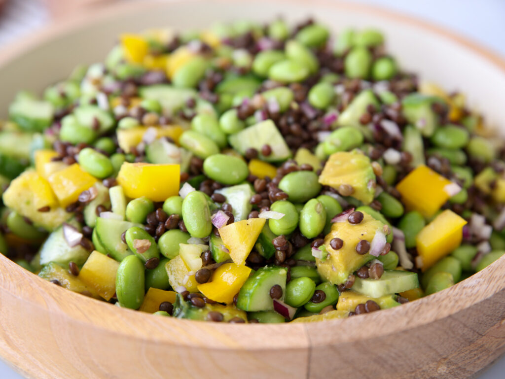 A bowl of salad with edamame, black lentils and vegetables