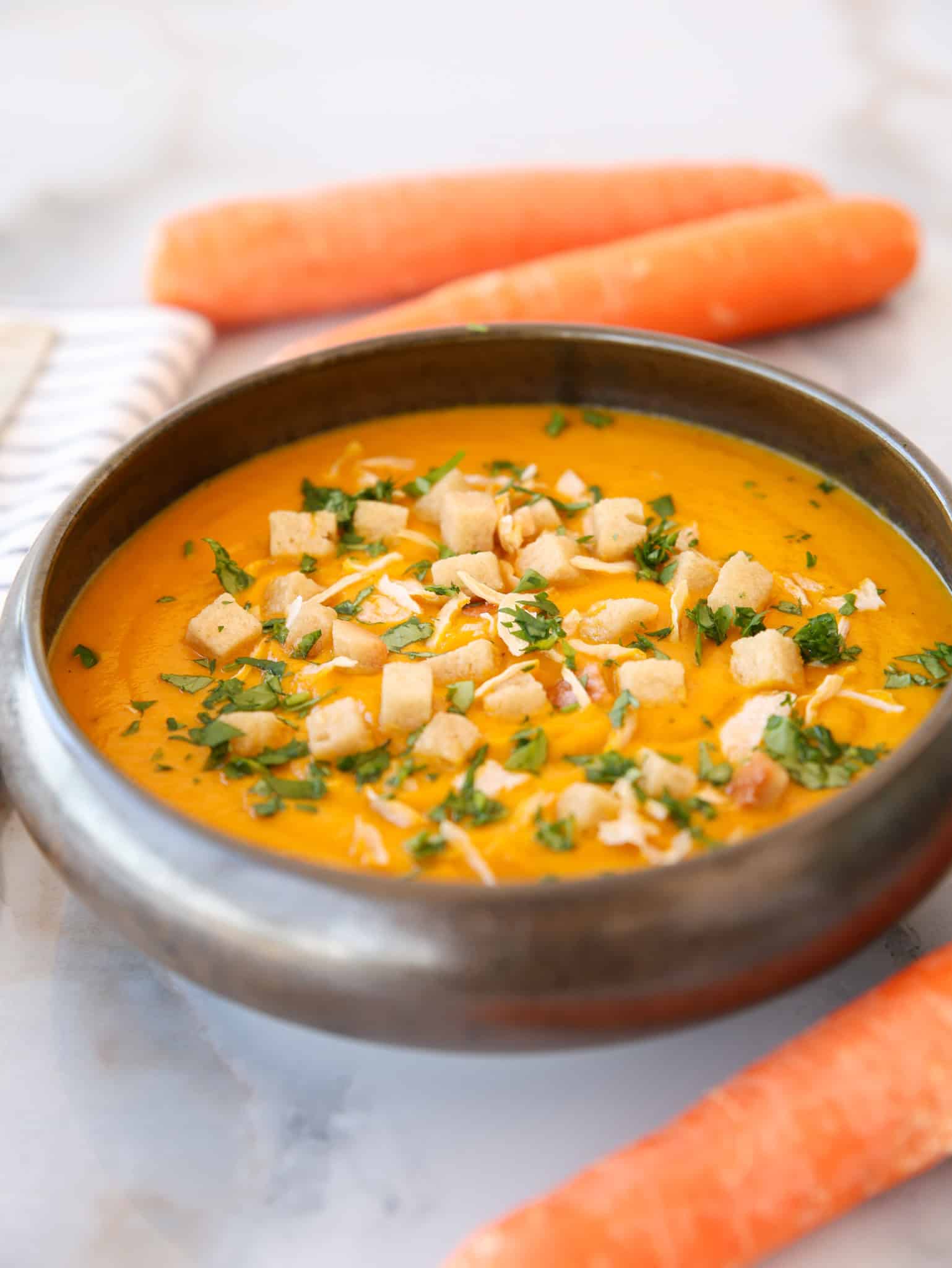 a dark bowl of fresh carrot and ginger soup