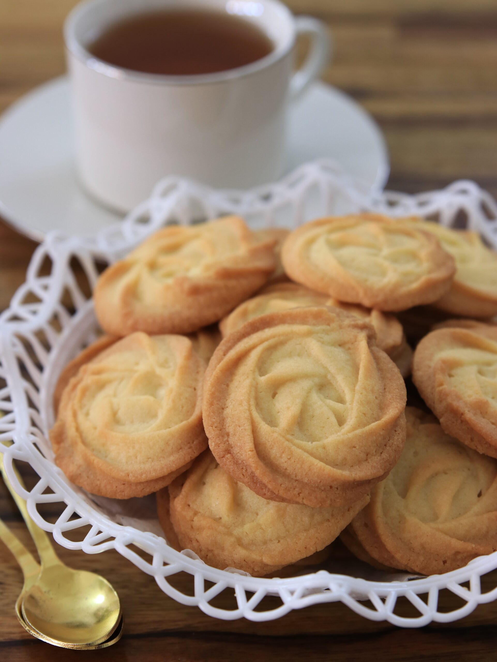 eggless butter cookies in a plate with a cup of tea